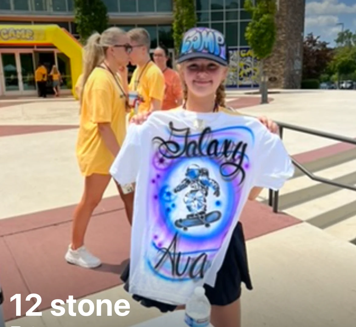 Guest holding a personalized airbrushed shirt at the 12Stone Church VBS conference