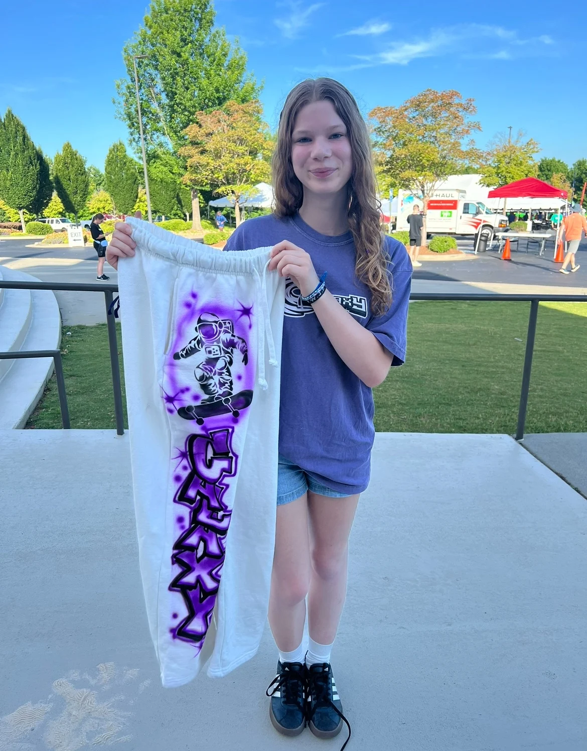 Guest holding a white item with purple airbrushed lettering