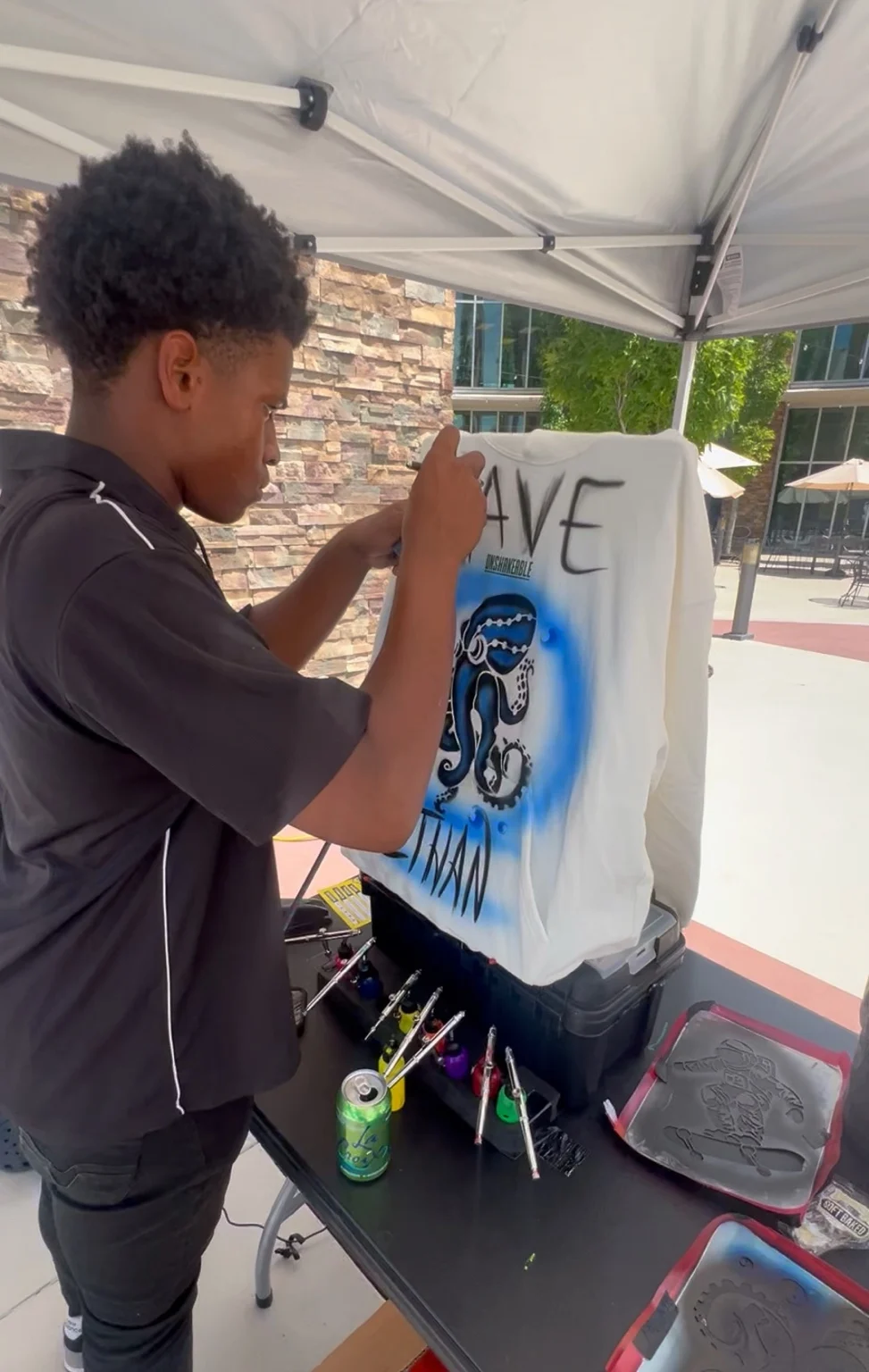 Artist painting a blue design on a white shirt at the VBS conference