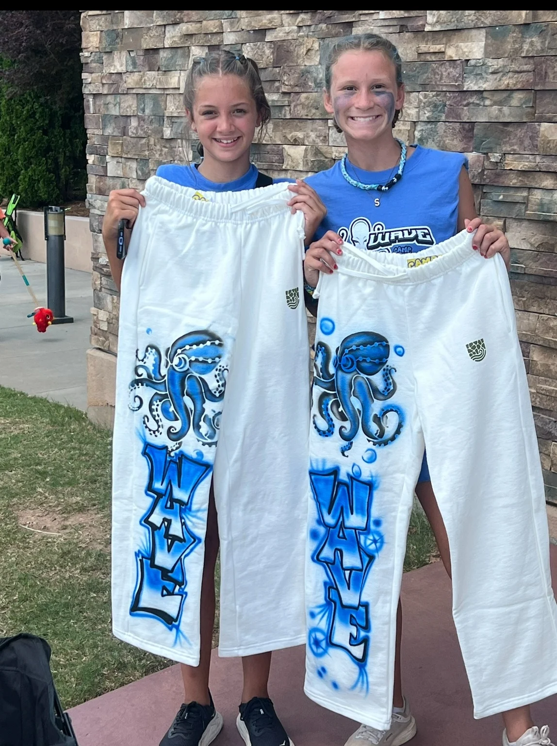 Two guests displaying blue airbrush designs at the conference
