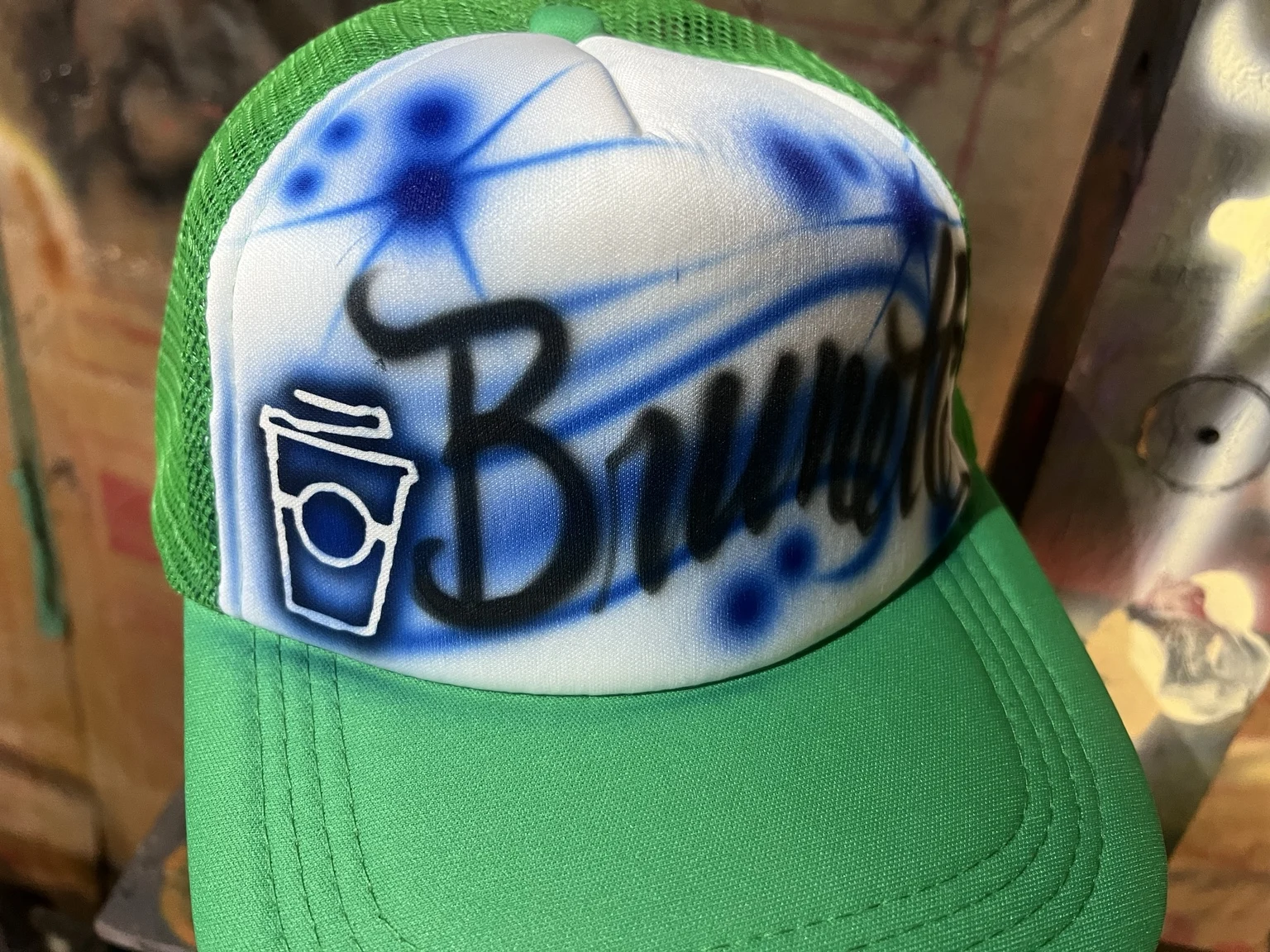 Green trucker hat with blue lettering and a coffee cup design at the 7 Brew Nashville event