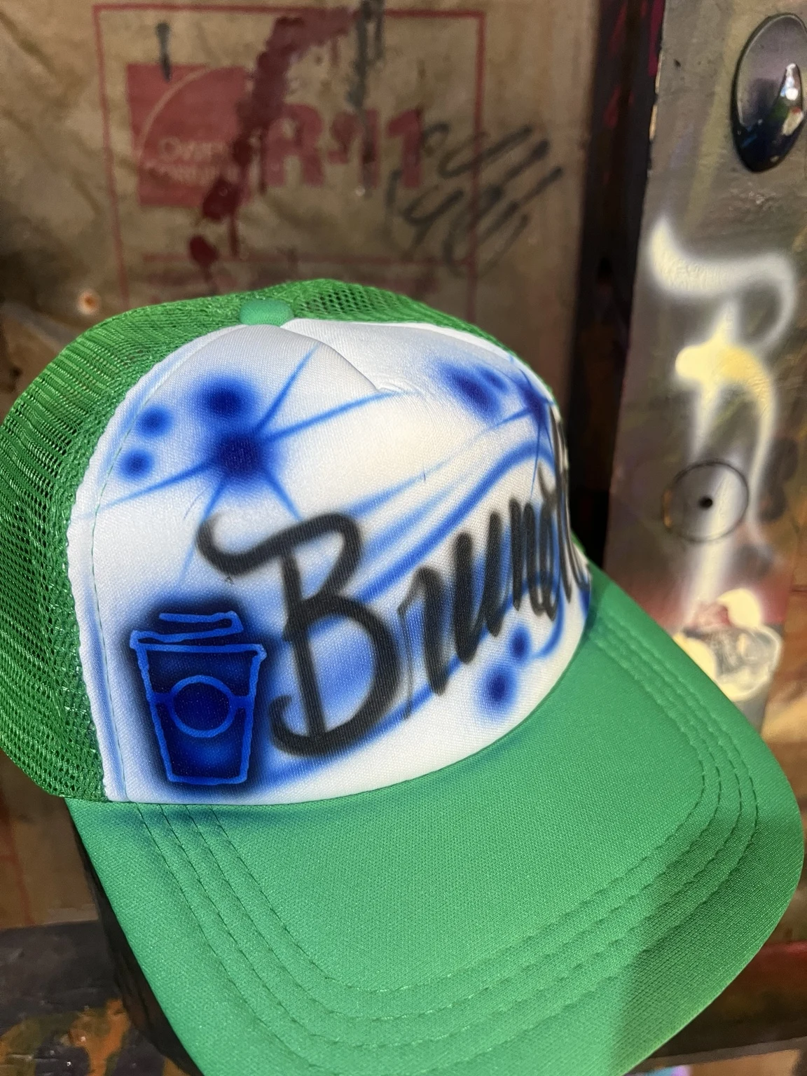 Angled view of a green coffee-themed trucker hat customized for 7 Brew in Nashville