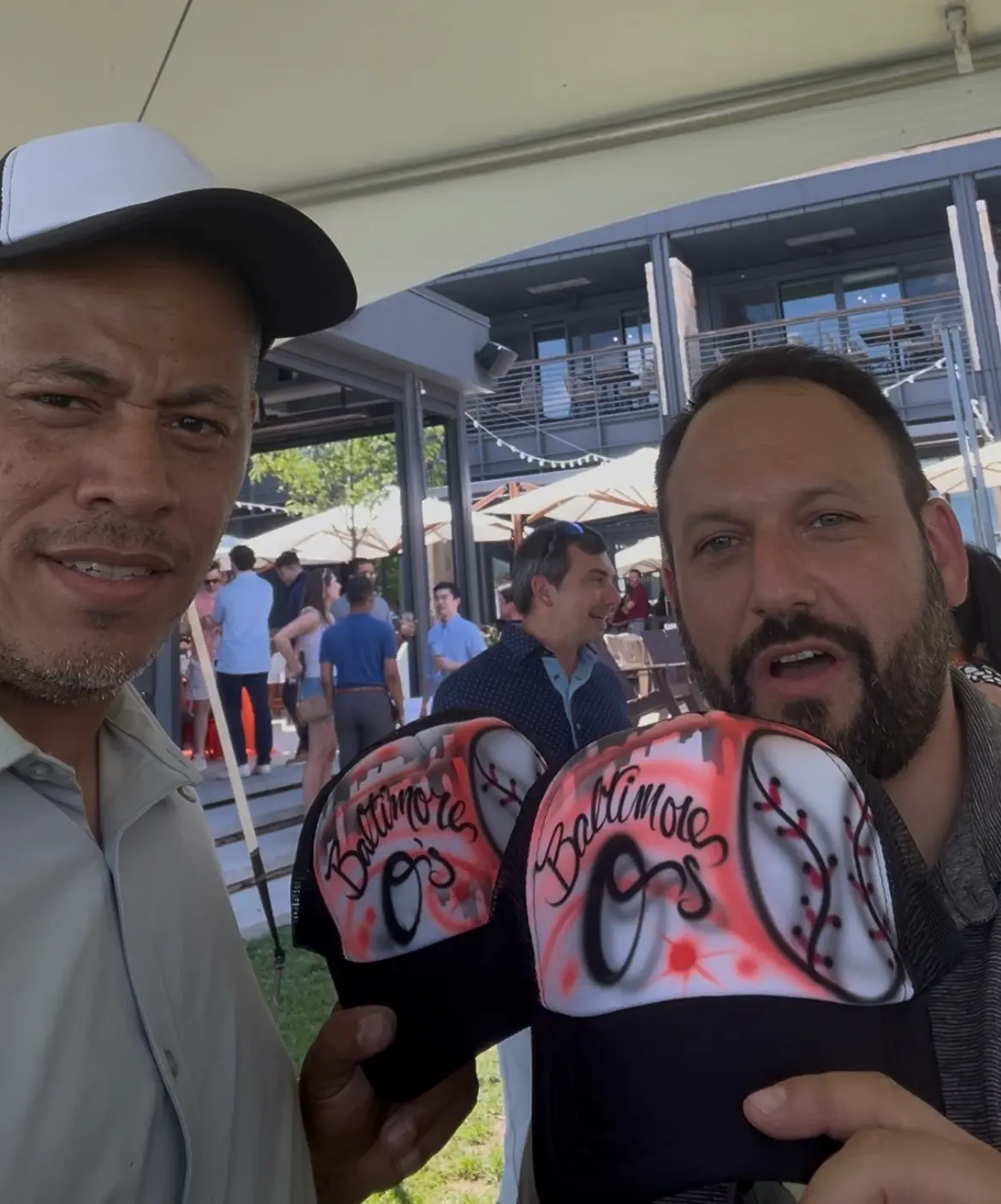 Artist and guest displaying Baltimore Orioles themed airbrushed hats