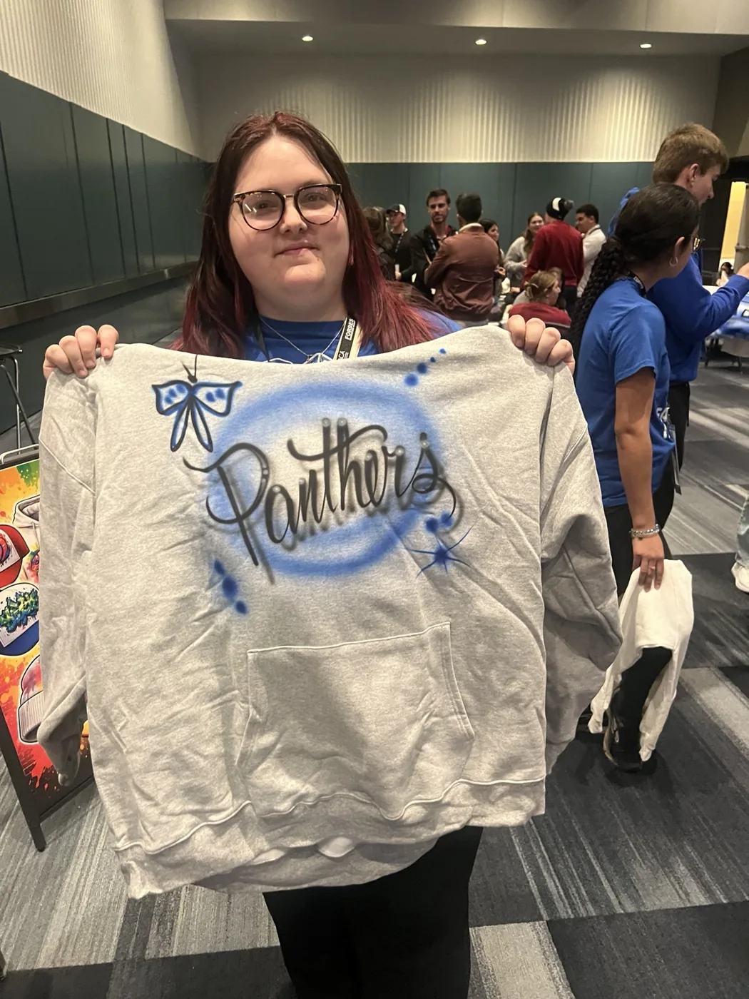 Student displaying a blue personalized airbrushed sweatshirt