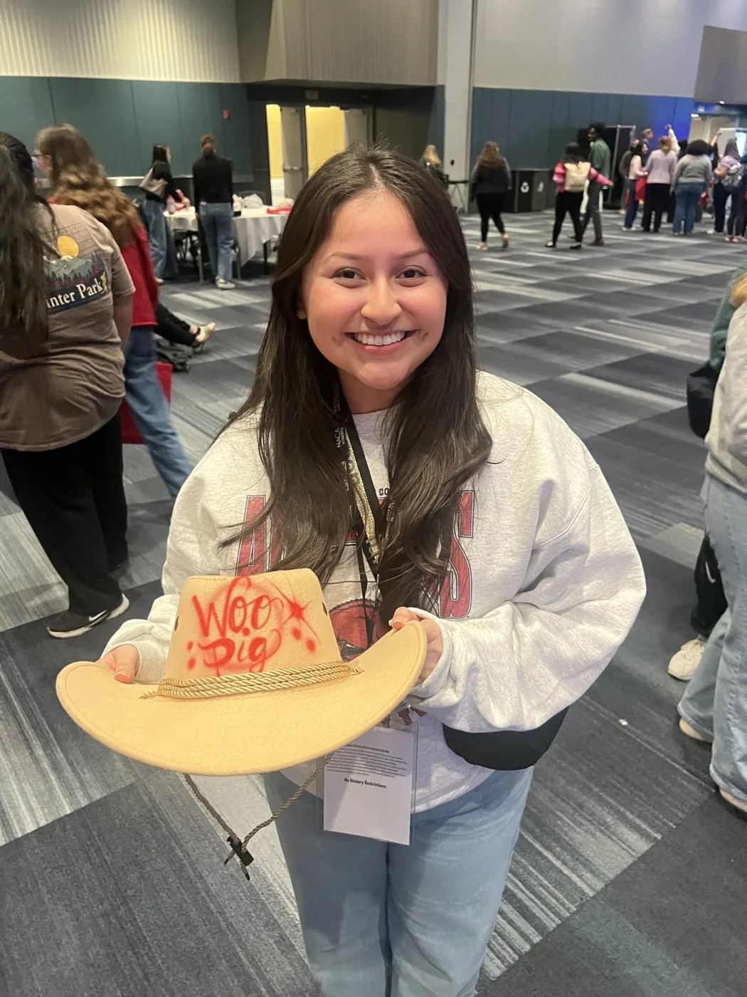 Student holding a custom airbrushed hat at a Birmingham college event