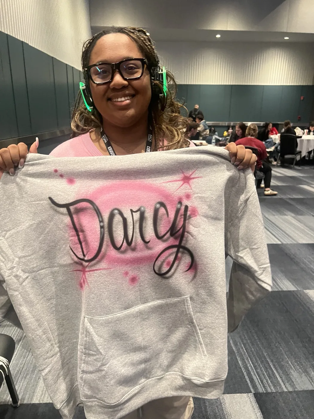 Student displaying a pink personalized airbrushed sweatshirt