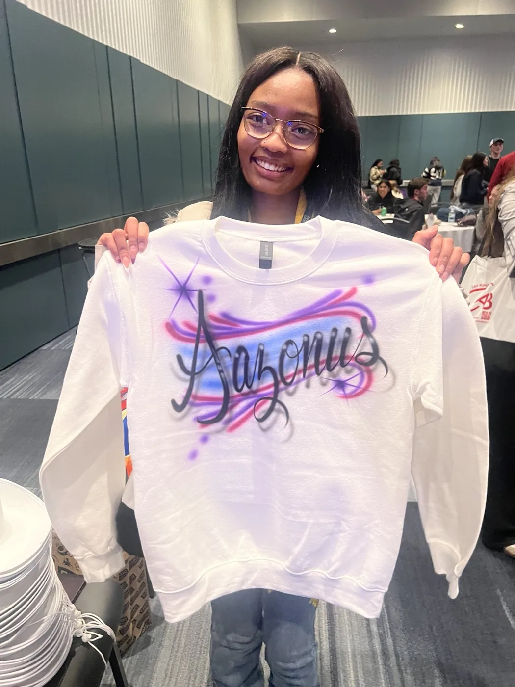 Student displaying a purple personalized airbrushed sweatshirt