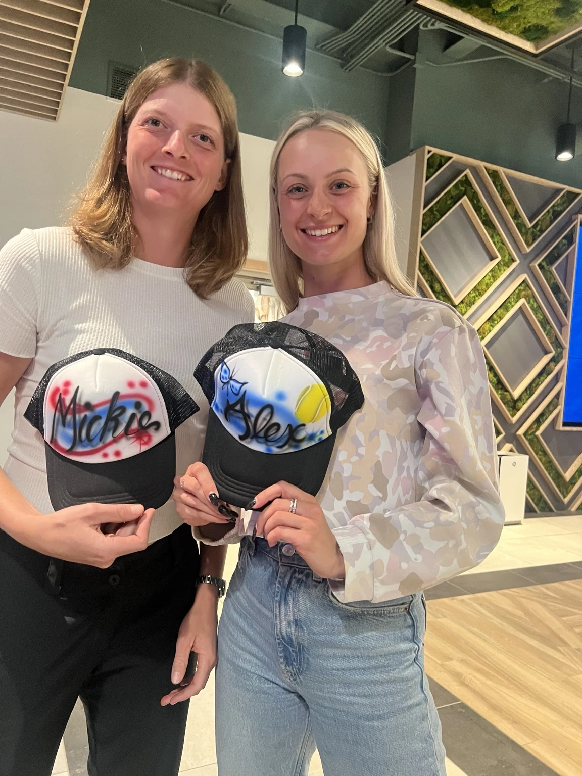 Two players displaying personalized trucker hats at the professional tennis tournament in Charleston, South Carolina