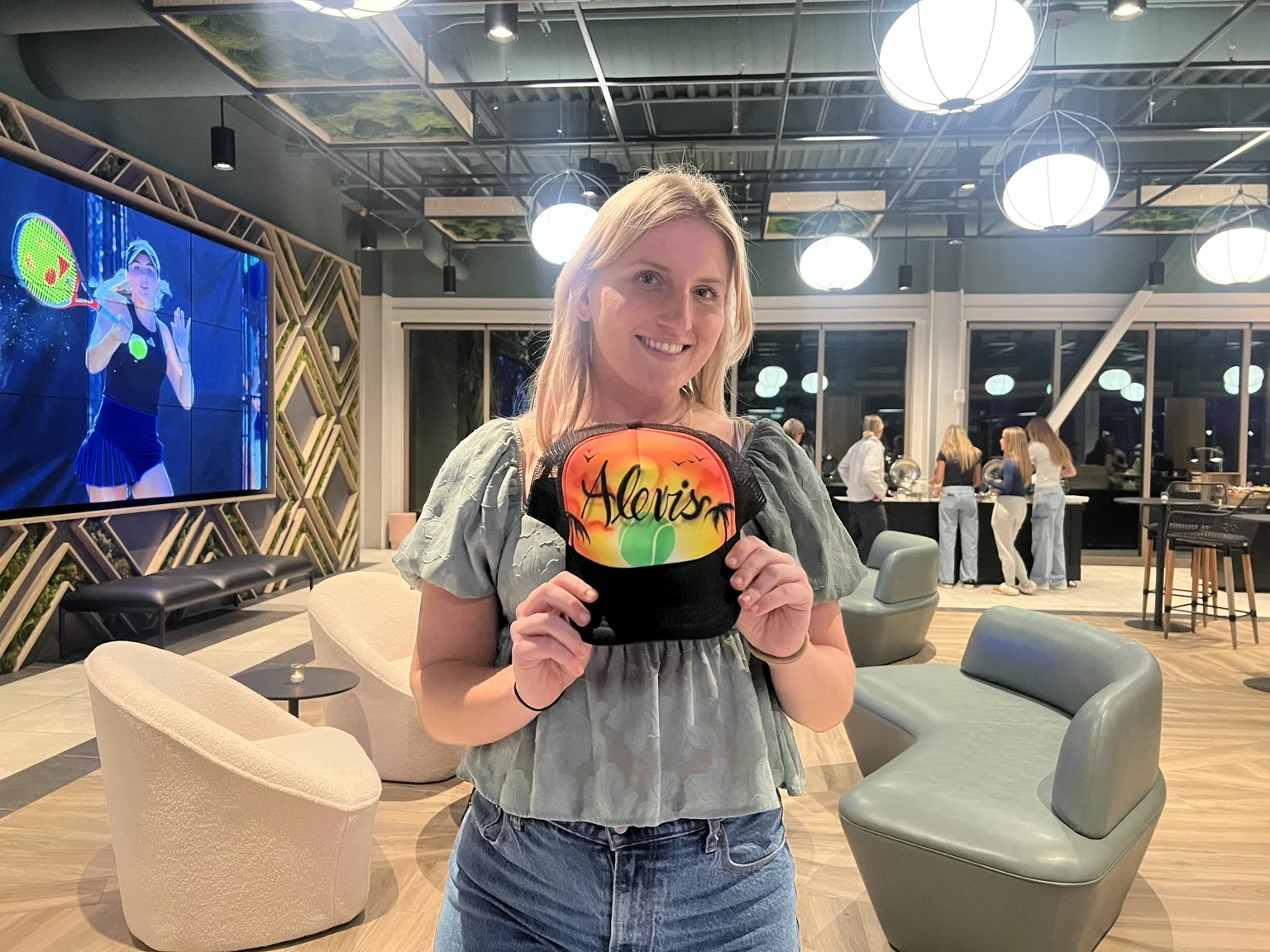 A player holding an orange and green personalized hat at the professional tennis tournament in Charleston, South Carolina