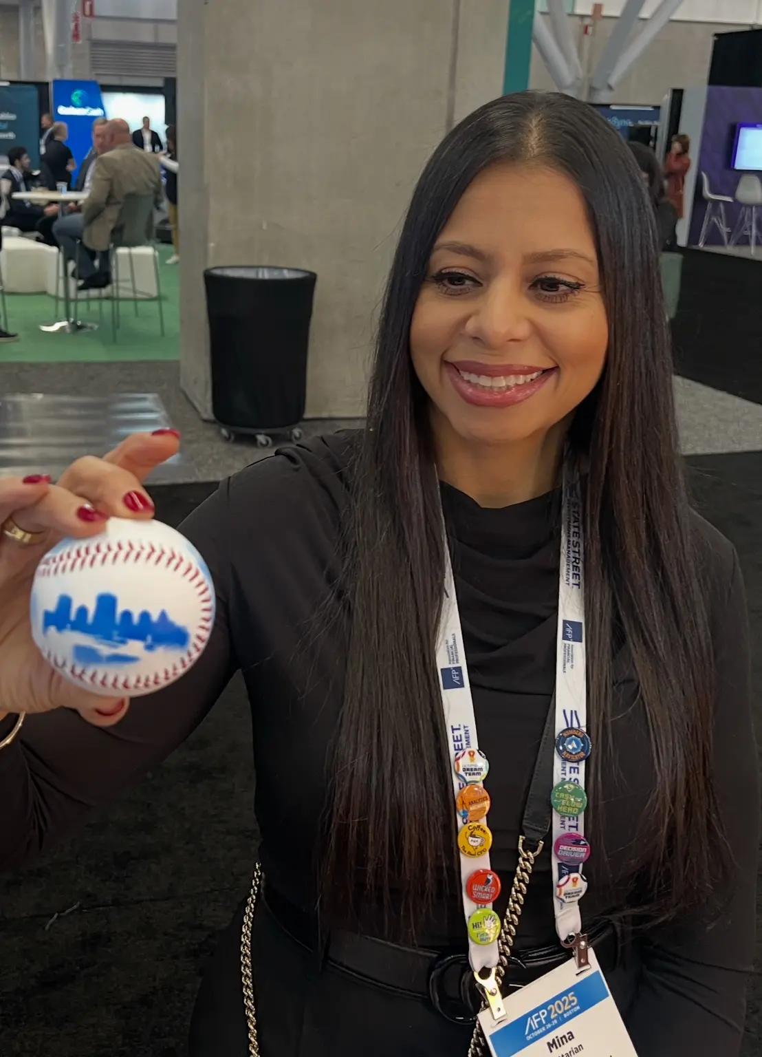 EY guest holding a personalized baseball with a blue Boston skyline design
