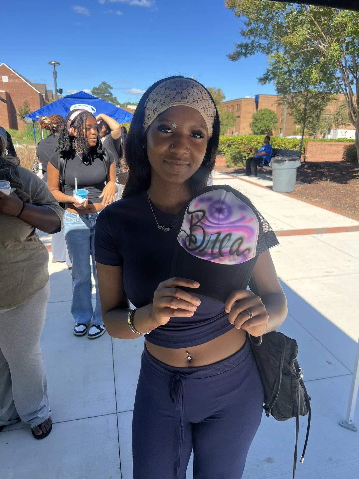 Guest holding a pink and purple personalized trucker hat at Fayetteville State University homecoming