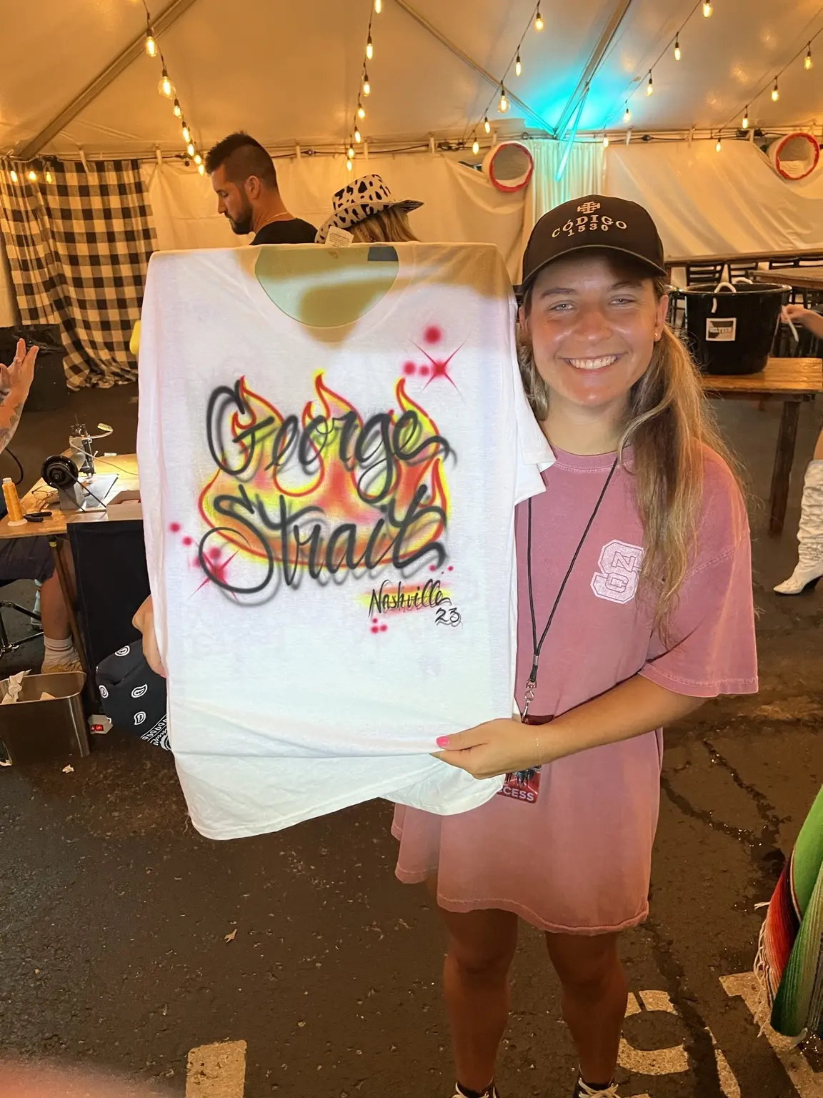 Backstage guest holding a personalized George Strait Nashville airbrushed shirt