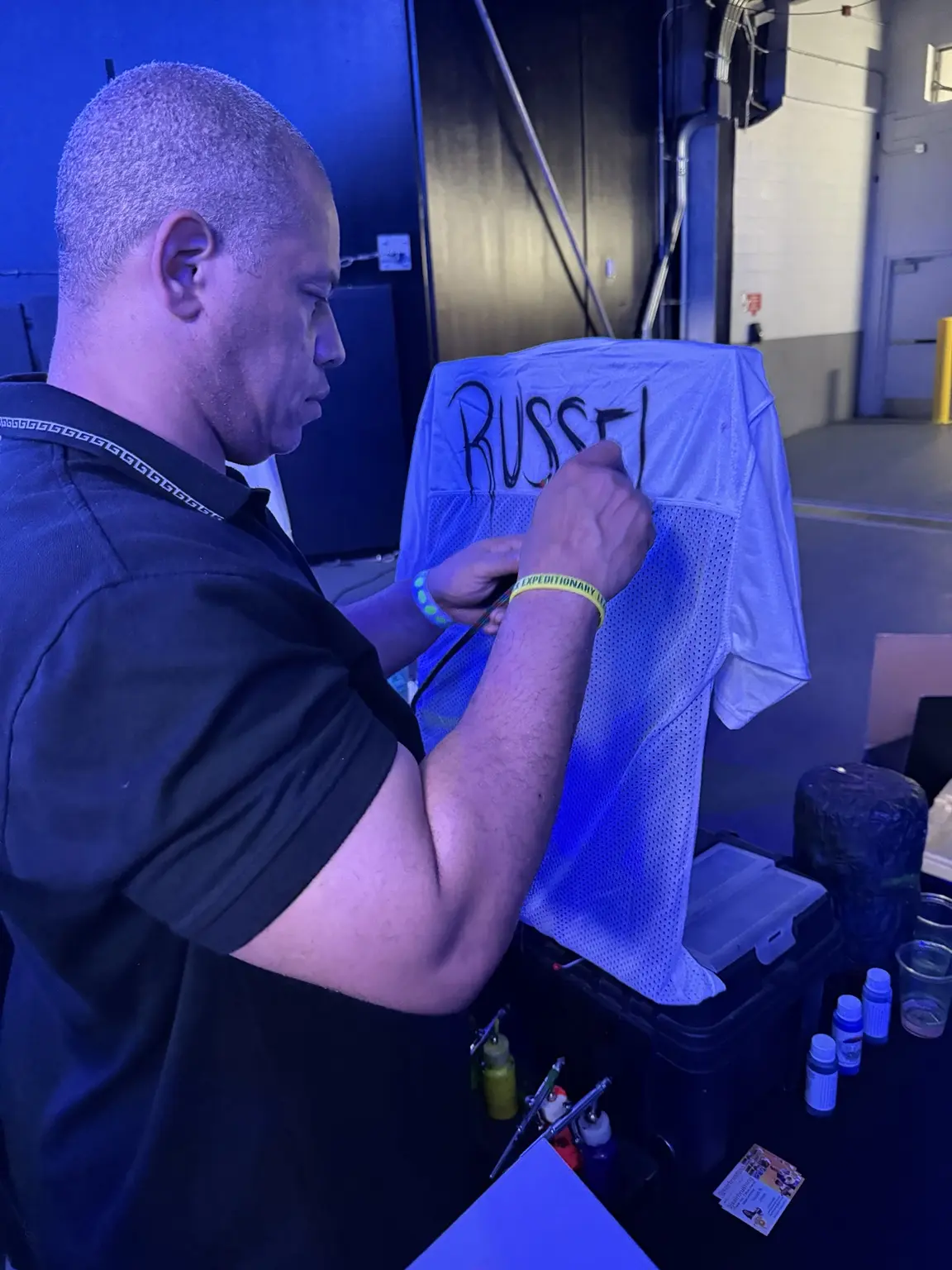 3JS artist airbrushing a personalized football jersey live at Mercedes-Benz Stadium