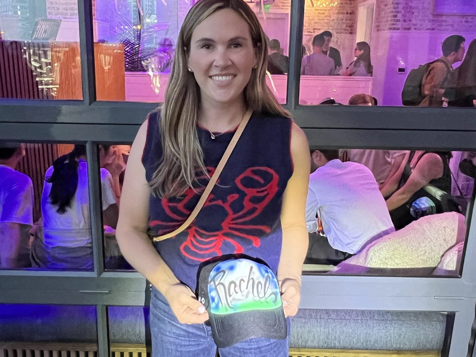 Guest holding a blue and green personalized trucker hat in Nashville, Tennessee