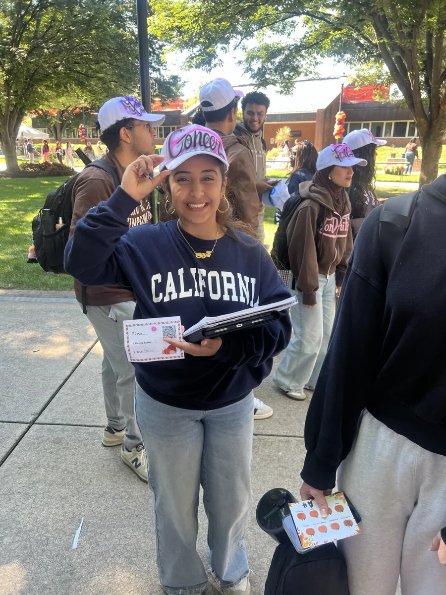 Guest wearing a pink personalized hat at the outdoor campus event