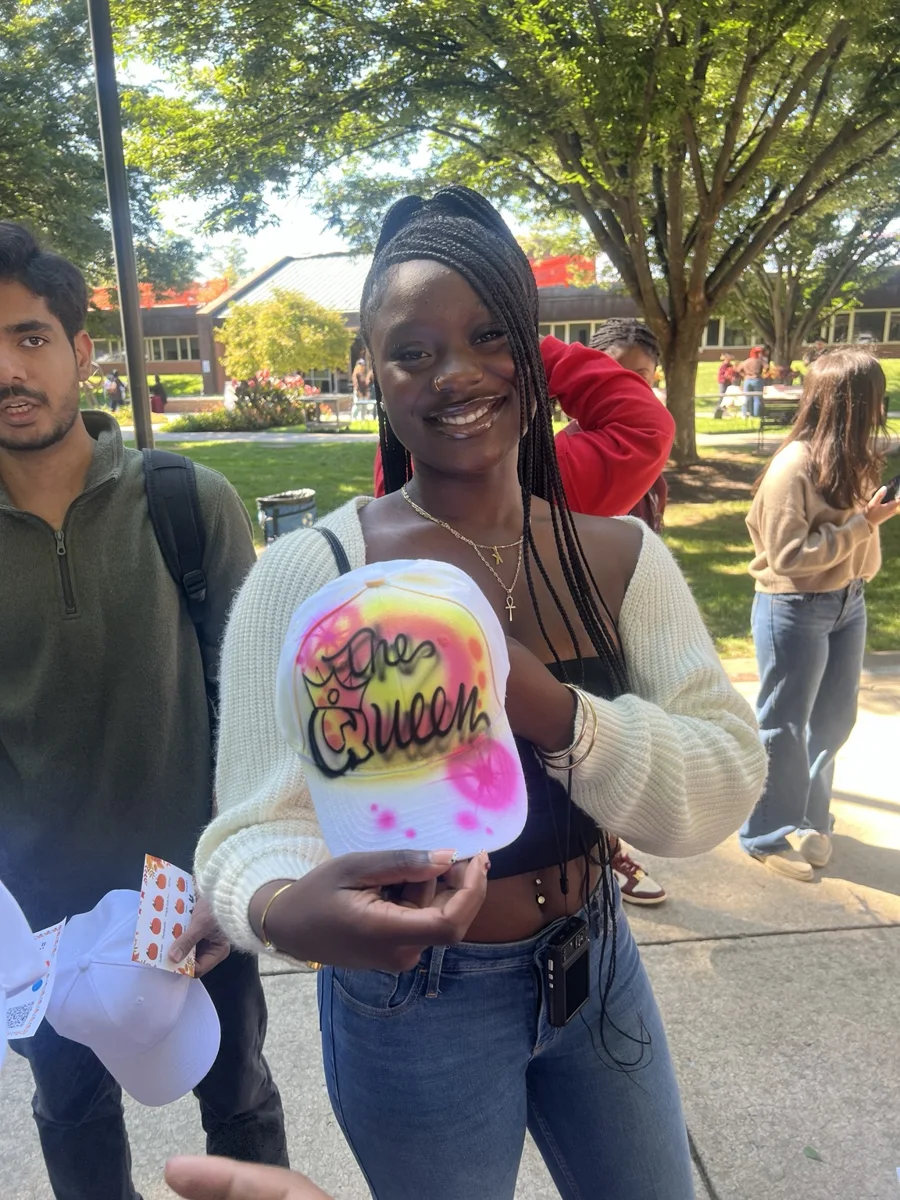 Guest holding a colorful personalized baseball hat at Penn State Harrisburg