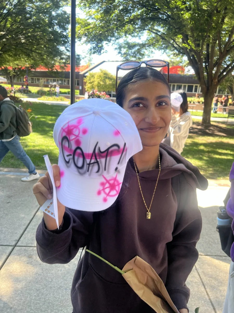 Guest showing a white baseball hat with pink airbrushed flowers and lettering