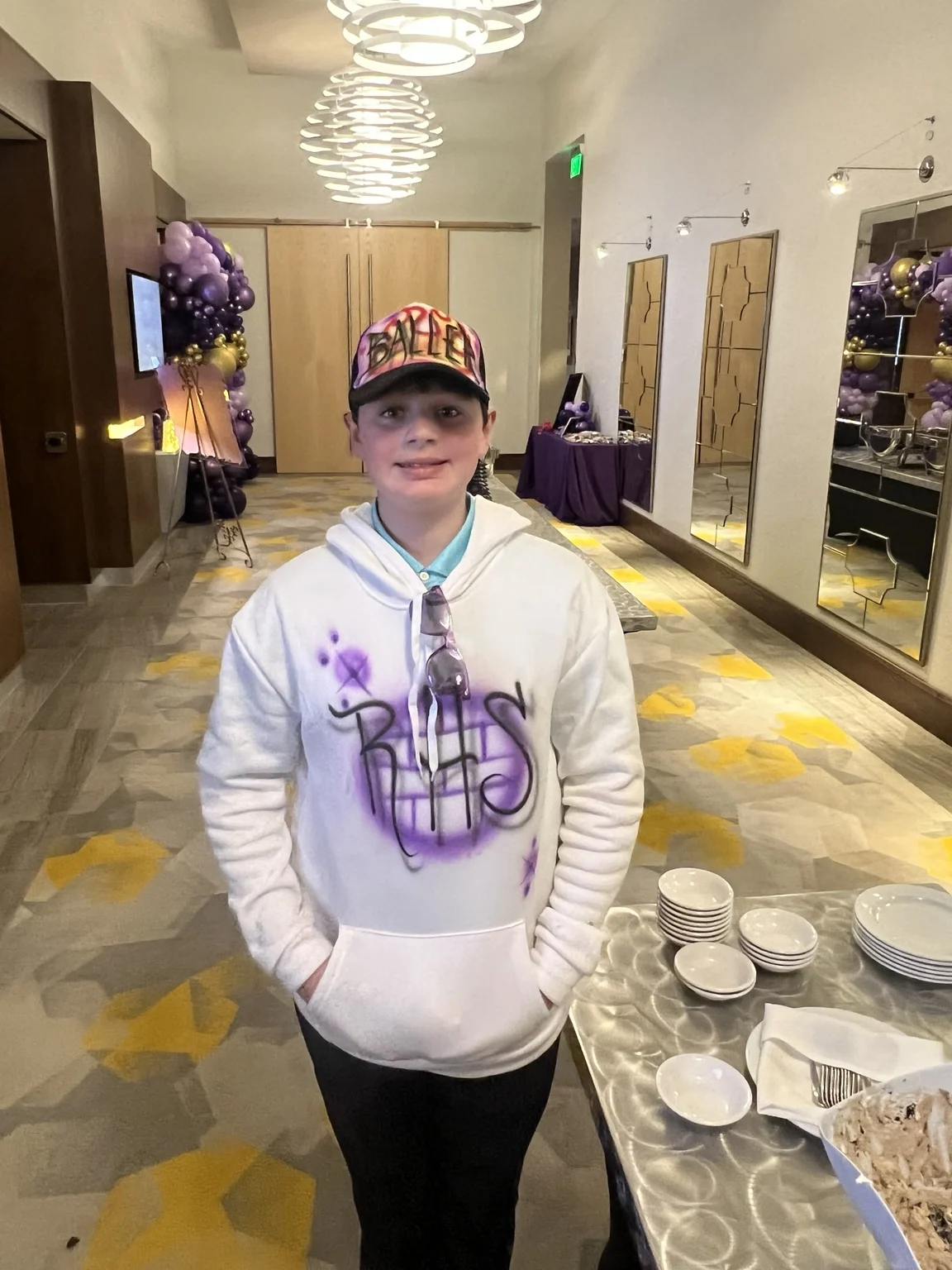 Guest wearing a purple airbrushed hoodie and a colorful trucker hat at an event in Portland, Oregon