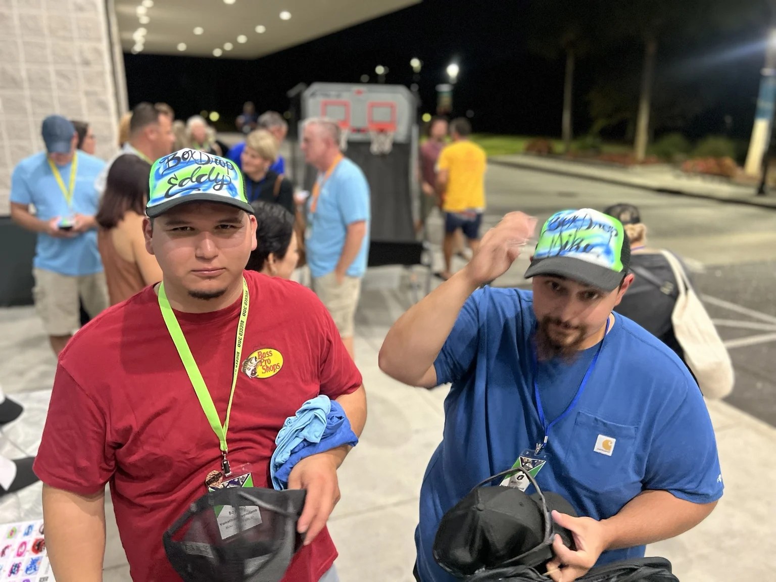 Two guests wearing matching green and blue custom trucker hats at an event in Portland, Oregon