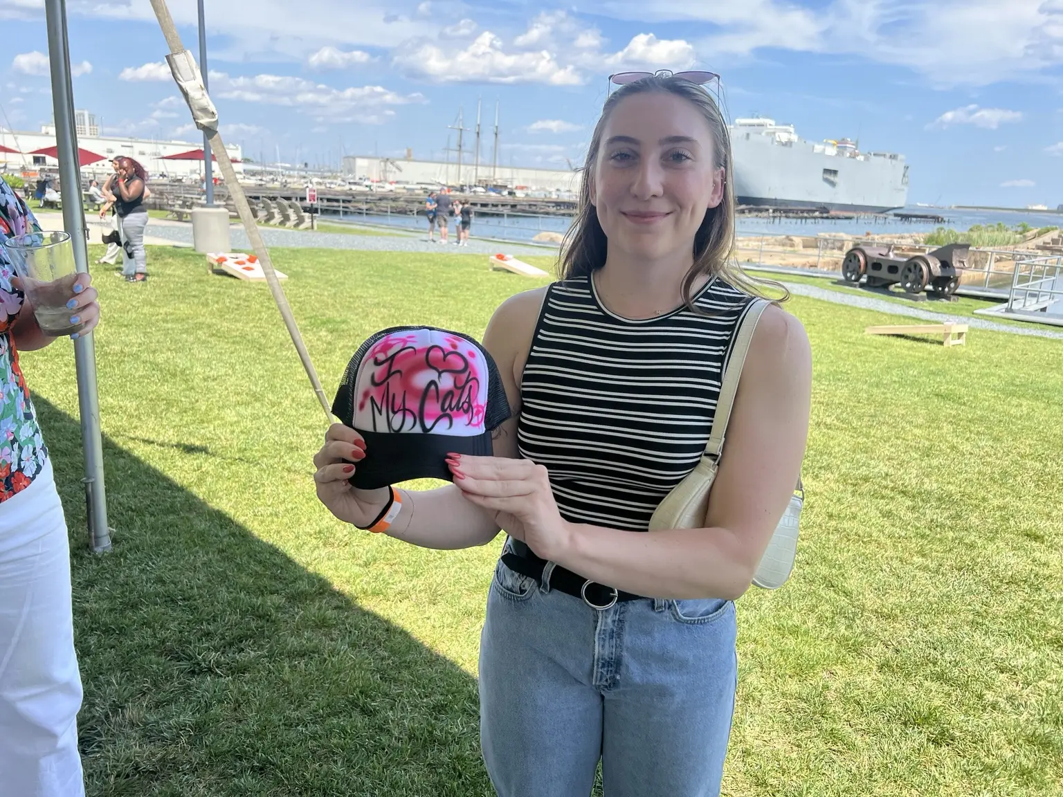 PwC guest holding a red and pink custom airbrushed hat by the Baltimore waterfront