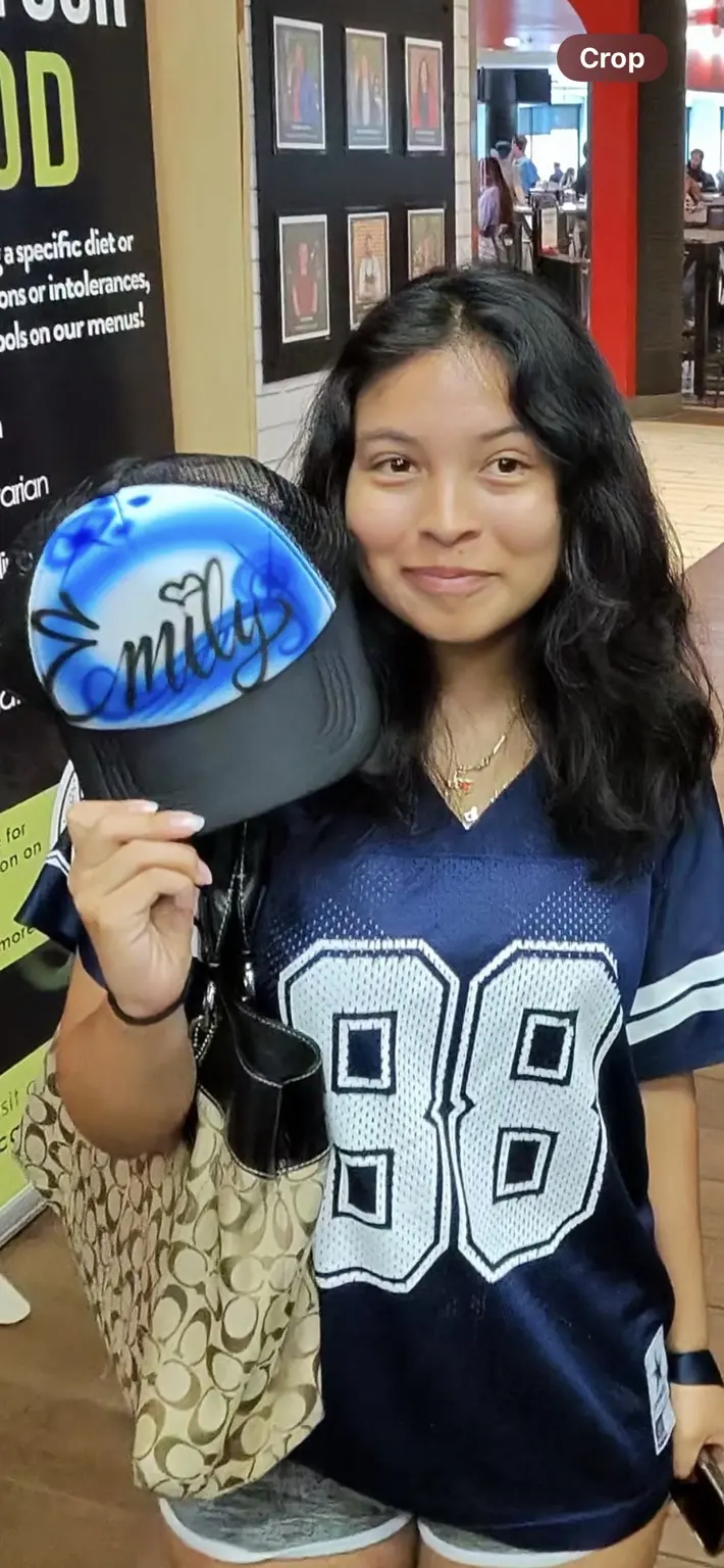 Radford University student holding a blue personalized airbrushed trucker hat