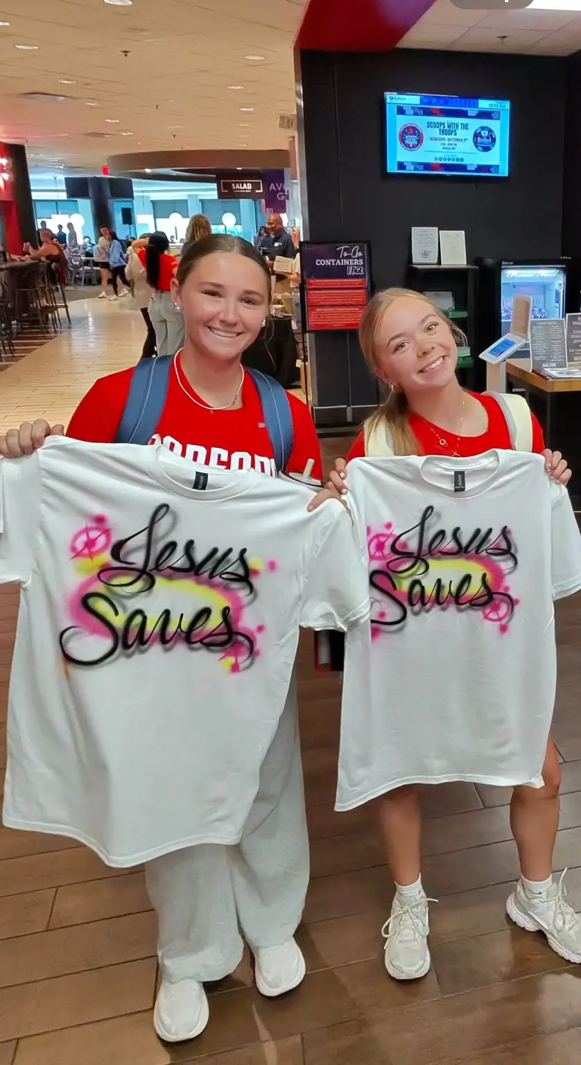 Two Radford University students showing personalized airbrushed T-shirts at a campus event in Virginia