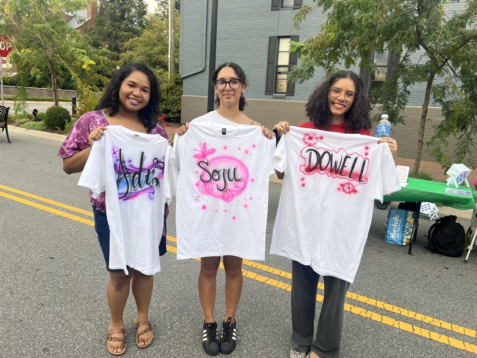 Roanoke College students displaying custom airbrushed shirts at the Fall Festival