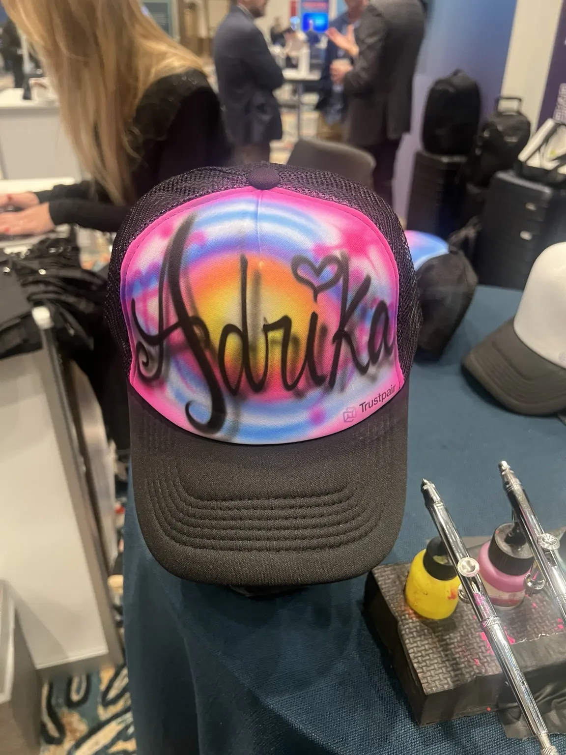Close-up of a personalized name hat being airbrushed at the Trustpair event
