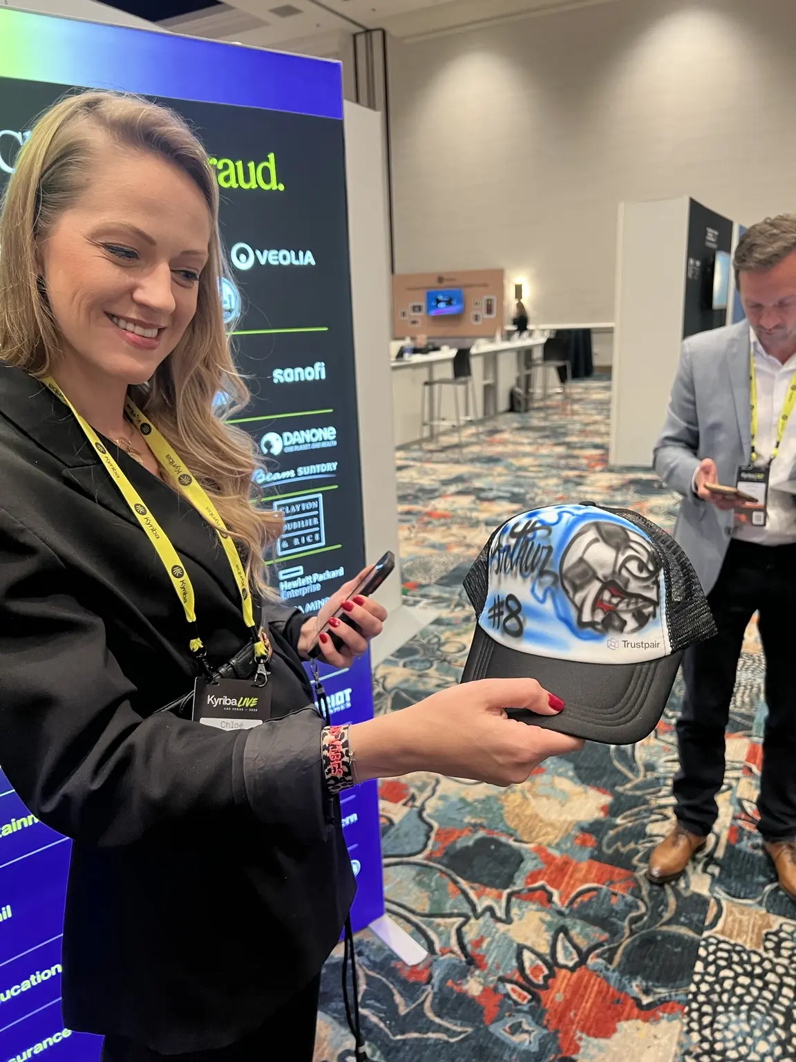 Trustpair guest holding a personalized airbrushed hat at a Las Vegas conference