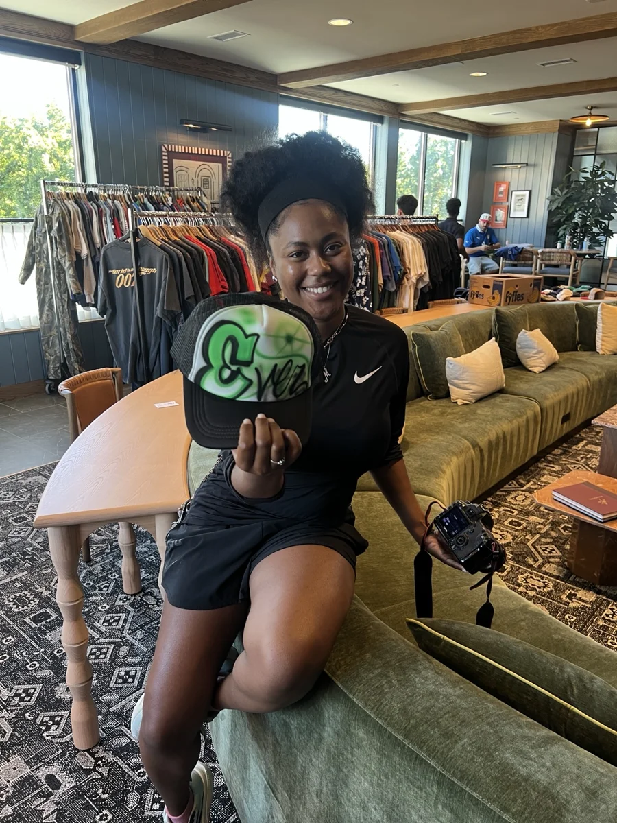 Guest holding a green custom airbrush trucker hat at the Knoxville customization activation.