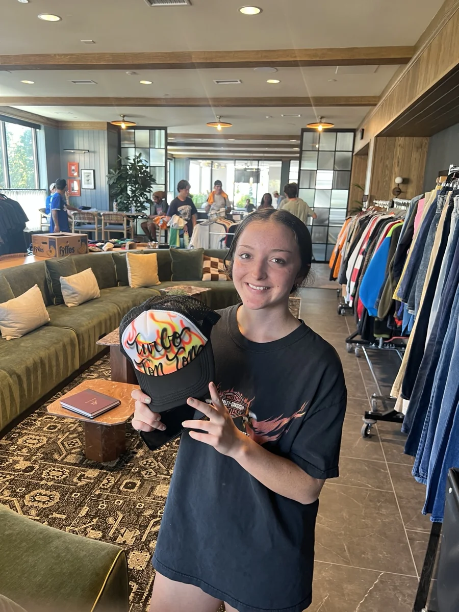 Guest holding an orange and yellow personalized trucker hat in Knoxville, Tennessee.
