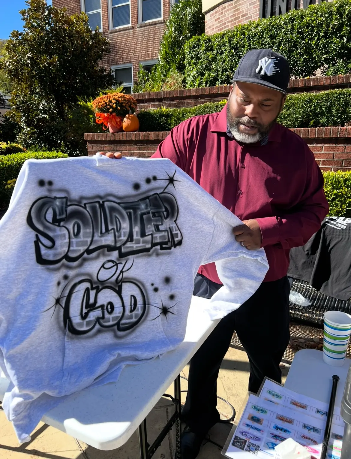 Student holding a Soldier of God custom airbrushed T-shirt at UPIKE