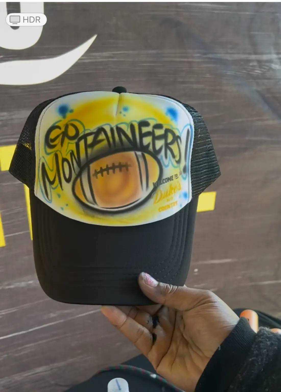Custom Go Mountaineers trucker hat with football artwork at a West Virginia university event