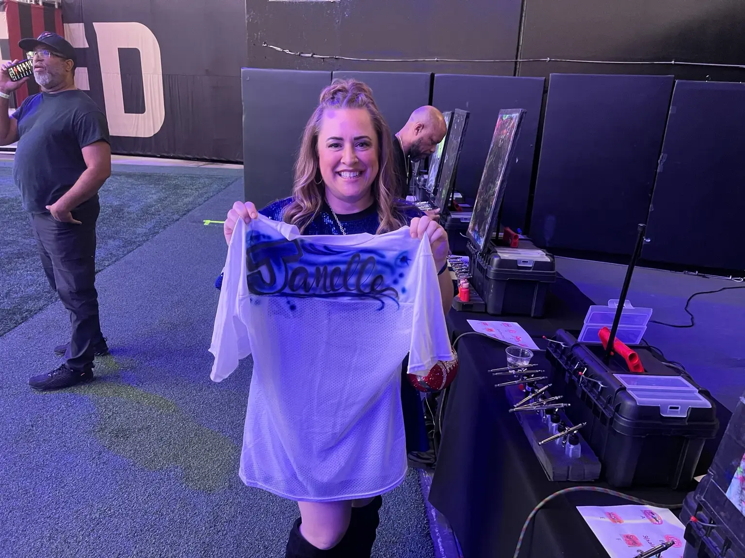 Guest holding her personalized airbrushed football jersey at Mercedes-Benz Stadium